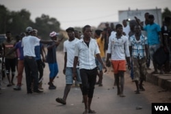 Supporters of the opposition Sierra Leone People's Party walk after clashing with police outside party headquarters in Freetown's Goderich neighborhood, March 7, 2018. (J. Patinkin/VOA)