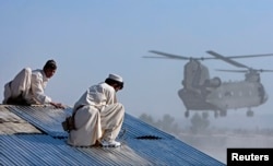 Afghan workers build a combat resupply area while a Chinook CH-47F transport helicopter prepares to land at FOB Salerno, Afghanistan on December 2, 2009.