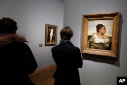 Visitors look at "Jeune orpheline au cimetiere" ("Orphan Girl at the Cemetery") by Eugene Delacroix at the Louvre, in Paris, March 27, 2018.