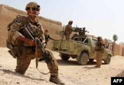 FILE - Afghan National Army commandos take position during a military operation in Helmand province, Oct. 2, 2016.