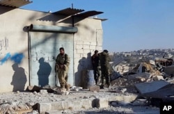 FILE - This photo provided by the Rumaf, a Syrian Kurdish activist group, which has been authenticated based on its contents and other AP reporting, shows Kurdish fighters watch people flee from rebel-held eastern neighborhoods of Aleppo, Nov. 27, 2016.