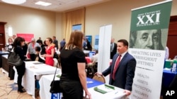 FILE - Corporate representatives speak with job seekers at a job fair in Pittsburgh, Pennsylvania, March 30, 2016.