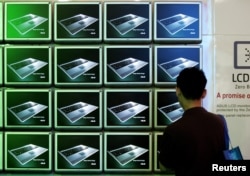 FILE - A visitor looks at ASUS computer screens at the Computex trade show in Taipei.