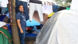 Josue Herman Sanchez Mendoza, 36, stands by the tent that he shares with his wife and a couple from Guatemala. (Dylan Baddour/VOA)