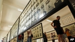 FILE - Tourists view portraits of victims executed by the Khmer Rouge regime at the Tuol Sleng Genocide Museum, formerly a notorious Khmer Rouge prison, in Phnom Penh, Cambodia, April 9, 2015.