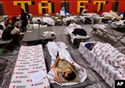 Evacuees from a wildfire rest on cots and blanket supplied by the Red Cross in the gymnasium at Taft Charter High School in the Woodland Hills section of Los Angeles on Nov. 9, 2018.