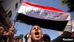 An anti-Houthi protester shouts slogan as he holds a Yemeni flag on which the words, "Neither death nor humiliation" during a demonstration in the southwestern city of Taiz, Feb. 9, 2015.