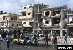 Syrian citizens gather at the scene where two blasts exploded in the pro-government neighborhood of Zahraa, in Homs province, Syria, Feb. 21, 2016. The Islamic State group claimed responsibility for this and another attack Sunday.