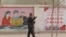 FILE - A farmer walks past government propaganda depicting ethnic minority residents reading the constitution with a slogan that reads, "Unity, Stability is fortune, Separatism and Turmoil is misfortune," near Kashgar in Xinjiang, northwestern China, on March 19, 2021.