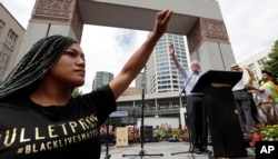 Mara Jacqueline Willaford of the Seattle chapter of Black Lives Matter, left, holds her fist overhead as Democratic presidential candidate Sen. Bernie Sanders, I-Vt., waves to greet the crowd before speaking at a rally in downtown Seattle, Washington, Aug. 8, 2015.