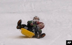 Wesley Lenahan, 4, right, and his brother Noah, 7, kick up snow as they sled down a hill at Fresh Pond, near Pollock Pines, California, Jan. 3, 2017.