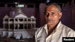 FILE - Hajari Lal, a devotee who participated and was injured during the demolition of Babri mosque, poses in front of the model of proposed Ram temple that Hindu groups want to build at a disputed religious site in Ayodhya, India, October 22, 2019…