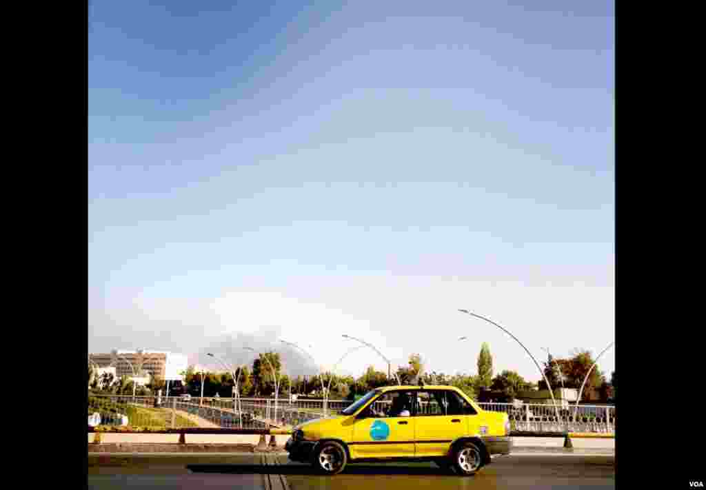 Gray smoke rises over a neighborhood on the outskirts of Damascus, where fighting between government forces and rebels continues. Residents are learning to live with the sounds of distant explosions and gunfire. (J. Weeks/VOA)