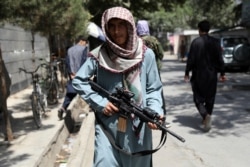 FILE - A Taliban fighter stands guard at a checkpoint in the Wazir Akbar Khan neighborhood in the city of Kabul, Afghanistan, Aug. 22, 2021.
