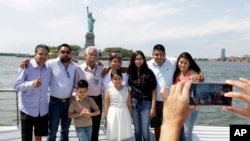 Luis Mendez Chanes, third left, poses with his daughter Marta Mendez, fourth left, as they reunite after 24 years in front of the Statue of Liberty aboard the Bateaux New York boat, July 5, 2017, in New York.