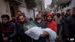 FILE - Mohammad Shouman carries the body of his daughter, Masa, who was killed in an Israeli bombardment of the Gaza Strip, during her funeral in Rafah, southern Gaza, Jan. 17, 2024. 