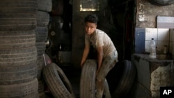 A boy carries a tire into the repair shop where he works in Cairo, Egypt, Wednesday, June 12, 2019. According to UN figures, 152 million children worldwide are working in almost every sector, with seven out of every ten children working in agriculture. (AP Photo/Maya Alleruzzo)