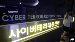 FILE - A woman walks by a sign at Cyber Terror Response Center of National Police Agency in Seoul, South Korea. 