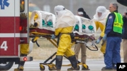 FILE - Health workers in protective suits transport a surgeon working in Sierra Leone who had been diagnosed with Ebola, at Nebraska Medical Center in Omaha, Neb., Nov. 15, 2014. 