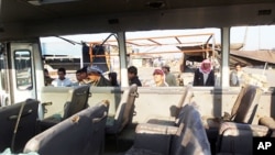 Iraqis look inside a bus damaged from shrapnel after a booby-trapped motorcycle exploded near a group of day laborers waiting for work in the Shi'ite district of Sadr City, January 5, 2012.