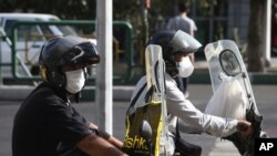 People on motorcycles wear face masks to help prevent the spread of the coronavirus in downtown Tehran, Iran, Sept. 20, 2020. Iran's president dismissed US efforts to restore all UN sanctions on the country.