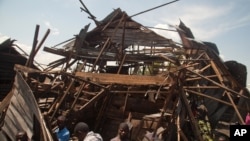 Men investigate the remains of a house struck hours earlier by deadly mortar fire, sparking angry protestors to take to the streets, in Goma, DRC, Aug. 24, 2013. 