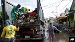 Workers collect garbage along a mud-covered road after floodwaters caused by Typhoon Goni rose inside their village in Batangas city, Batangas province, south of Manila, Philippines on Nov. 2, 2020. 