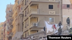 People inspect the area where a building collapsed in Gesr al-Suez, Cairo, Egypt, March 27, 2021. 