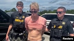 FILE - Ryan W. Routh, suspected of attempting to assassinate former President Donald Trump, stands handcuffed between two Martin County deputies after his arrest near Palm City, Florida, Sept. 15, 2024. (Martin County Sheriff's Office/Handout via Reuters)