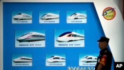 FILE - A security official stands near a display showing different models of Chinese trains ahead of the 2018 Forum on China-Africa Cooperation in Beijing, Aug. 30, 2018. Chinese funds for projects like railroads have flooded into Africa in recent years.