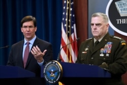 FILE - Defense Secretary Mark Esper, left, standing with Joint Chiefs​ Chairman Gen. Mark Milley, right, speaks during a news conference at the Pentagon in Washington, Dec. 20, 2019.