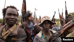 FILE - Caption SPLA-IO rebels hold up guns in Yondu, the day before an assault on government SPLA (Sudan People's Liberation Army) soldiers in the town of Kaya, on the border with Uganda, South Sudan, Aug. 25, 2017.