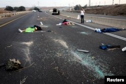 A man takes a photo of dead people strewn across a road n the Sderot area, southern Israel, following a mass-infiltration by Hamas gunmen from the Gaza Strip, Oct. 7, 2023.