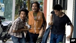 'Red shirt' anti-governement protesters carry a civilian after he was allegedly shot by a Thai army sniper near Ragprarop intersection during ongoing clashes in Bangkok, 15 May 2010