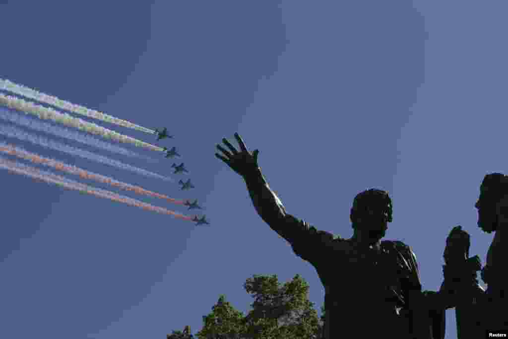 Russian military aircraft trail smoke in the colors of the Russian tricolor above the Monument to Minin and Pozharsky during the Victory Day Parade in Moscow's Red Square.