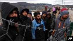 Migrants watch Bosnian soldiers put up tents at the Lipa camp outside Bihac, Bosnia, Jan. 1, 2021. Hundreds of migrants have been stuck in a burned-out camp in the northwest of the country in winter weather and with no facilities.