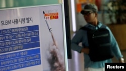 A passenger walks past a TV screen broadcasting a news report on North Korea's submarine-launched ballistic missile fired from North Korea's east coast port of Sinpo, at a railway station in Seoul, South Korea, August 24, 2016.