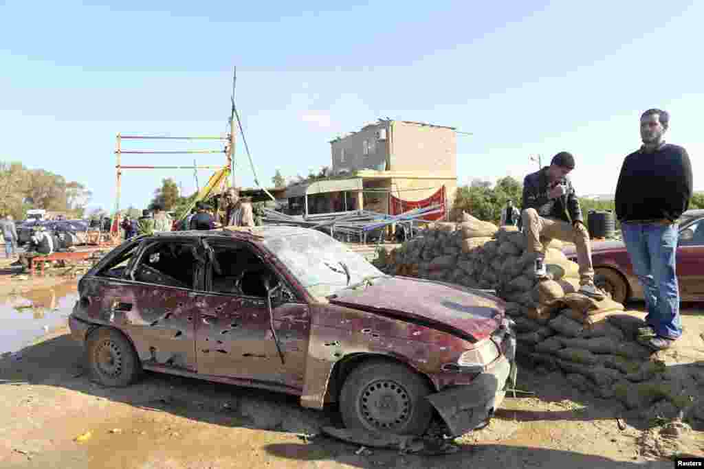 Men look at the scene near a military base 50 km outside Benghazi, after a suicide bomber detonated a truck packed with explosives at an army checkpoint, Barsis, Libya, Dec. 22, 2013.&nbsp;