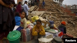 Warga duduk dengan barang-barang miliknya di luar sebuah kuil yang hancur di Alun-alun Bashantapur Durbar setelah gempa di Kathmandu, Nepal (25/4). (Reuters/Navesh Chitrakar)