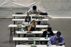 People fill out a form before receiving the Pfizer-BioNTech COVID-19 vaccine, in a vaccination center in Lyon, central France, July 7, 2021.