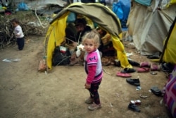 A child walks next to tents in a migrant camp set up near the Turkish-Greek border in Pazarkule, Edirne region, Turkey, March 10, 2020.