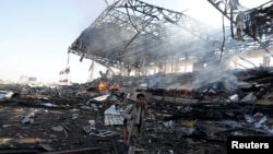 A Houthi fighter talks on the phone as he walks at the site of an airstrike on a parade square in Sana'a, Yemen, Nov. 5, 2017. 
