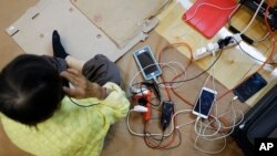 FILE - Cell phones and an electric shaver belonging to evacuees are charged at a shelter at Florida International University ahead of Hurricane Irma in Miami, Sept. 9, 2017.