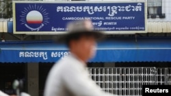 FILE - A man rides a motorcycle past the Cambodia National Rescue Party (CNRP) headquarters in Phnom Penh, Nov. 17, 2017. 