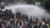 Police officers spray water using a canon to disperse demonstrators during a protest against the government's labour reforms in a polarizing jobs creation bill in Jakarta, Oct. 8, 2020.