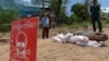 FILE - A Cambodian Mine Action Center (CMAC) member (L) and policeman keep watch behind a Mark 82 bomb in Kandal province on May 21, 2015. 