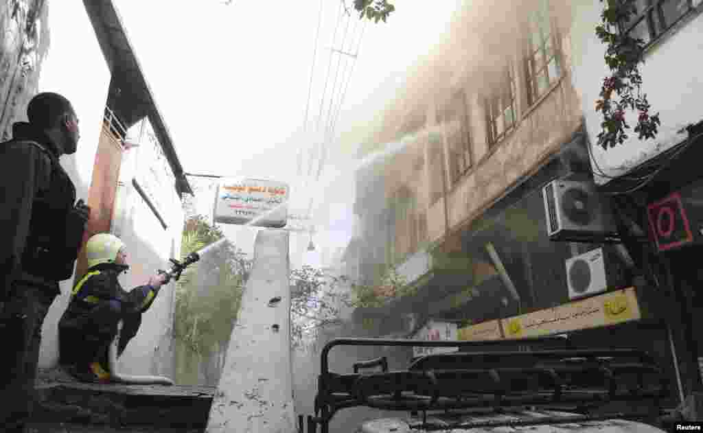 Firefighters try to extinguish a fire after a mortar bomb landed in Damascus, in this handout photograph distributed by Syria's national news agency SANA, Oct. 15, 2013.
