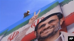 A worker fixes a huge poster of Iranian President Mahmoud Ahmadinejad during preparations for his visit to the southern village of Bint Jbeil, Lebanon, 12 Oct 2010