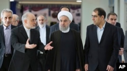 FILE - President Hassan Rouhani (center) listens to head of Iran's Atomic Energy Organization Ali Akbar Salehi (left) while attending a ceremony marking the national day of nuclear technology in Tehran, Iran, Thursday, April 7, 2016. Iran's Health Minister Hassan Ghazizadeh Hashemi is at right.