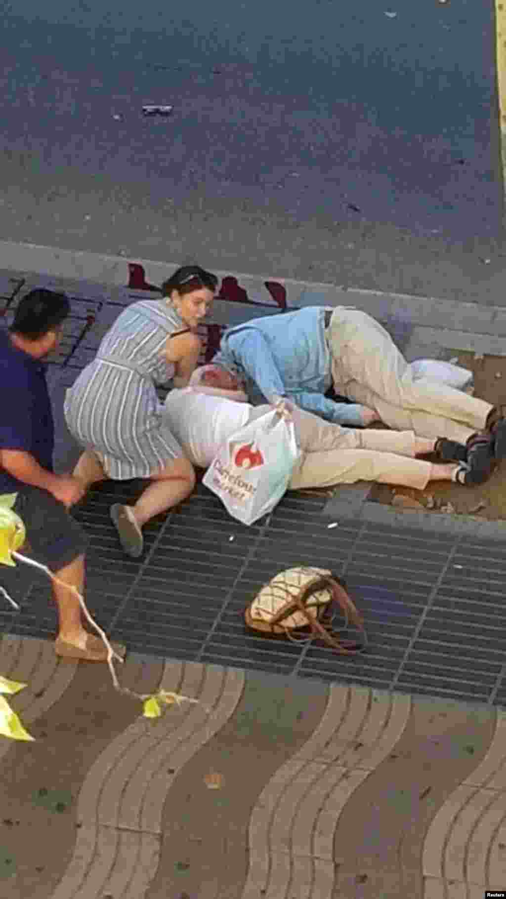People attend to injured persons at the scene after a van crashed into pedestrians near the Las Ramblas avenue in central Barcelona, Spain, Aug. 17, 2017.